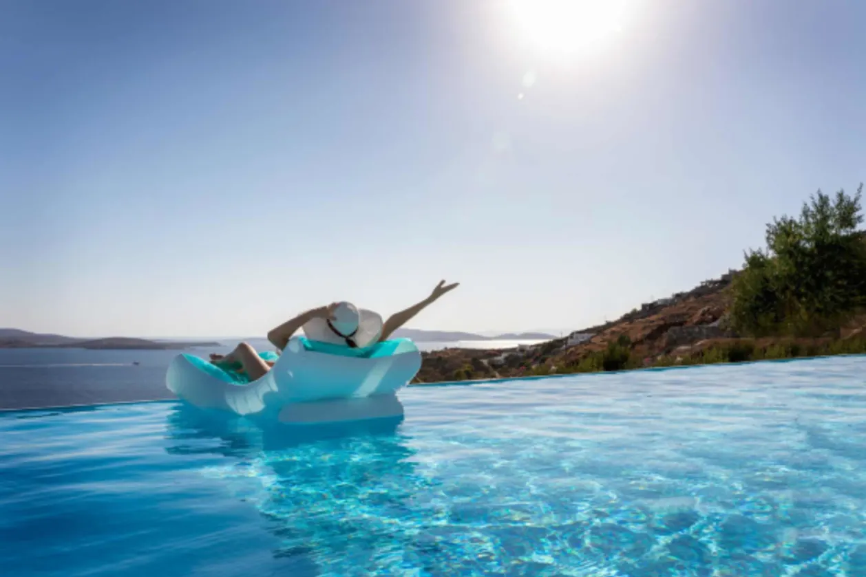 woman floating in infinity pool over Mediterranean